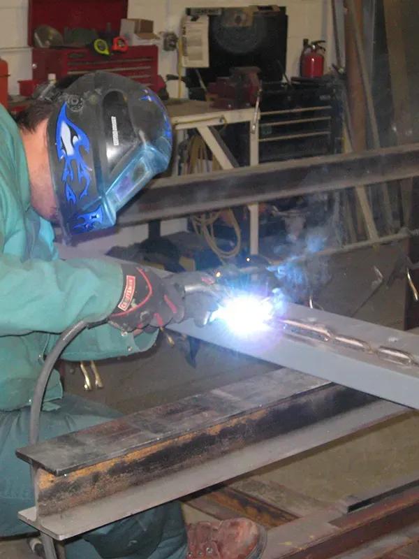 Welder working on commercial door frame illustrating installation complexity and labor costs.